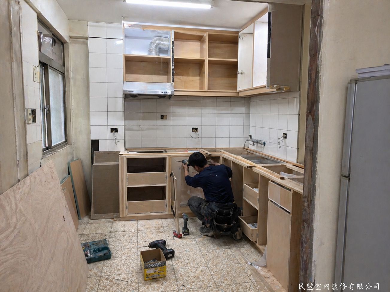 民豐室內裝修-客廳水電木作油漆地板暨廚浴翻新-拆除舊廚具後，師傅依業主需求訂製L型木作廚具，上下櫃骨架精準安裝，抽油煙機預留位置，整體施工有條不紊