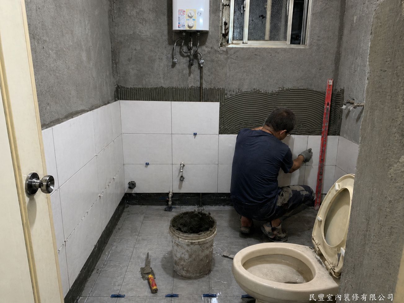 民豐室內裝修-客廳水電木作油漆地板暨廚浴翻新-師傅以水泥砂漿打底後，貼設灰色系新磁磚，地磚、壁磚分層施作，接縫整齊均勻，水平垂直精準控制