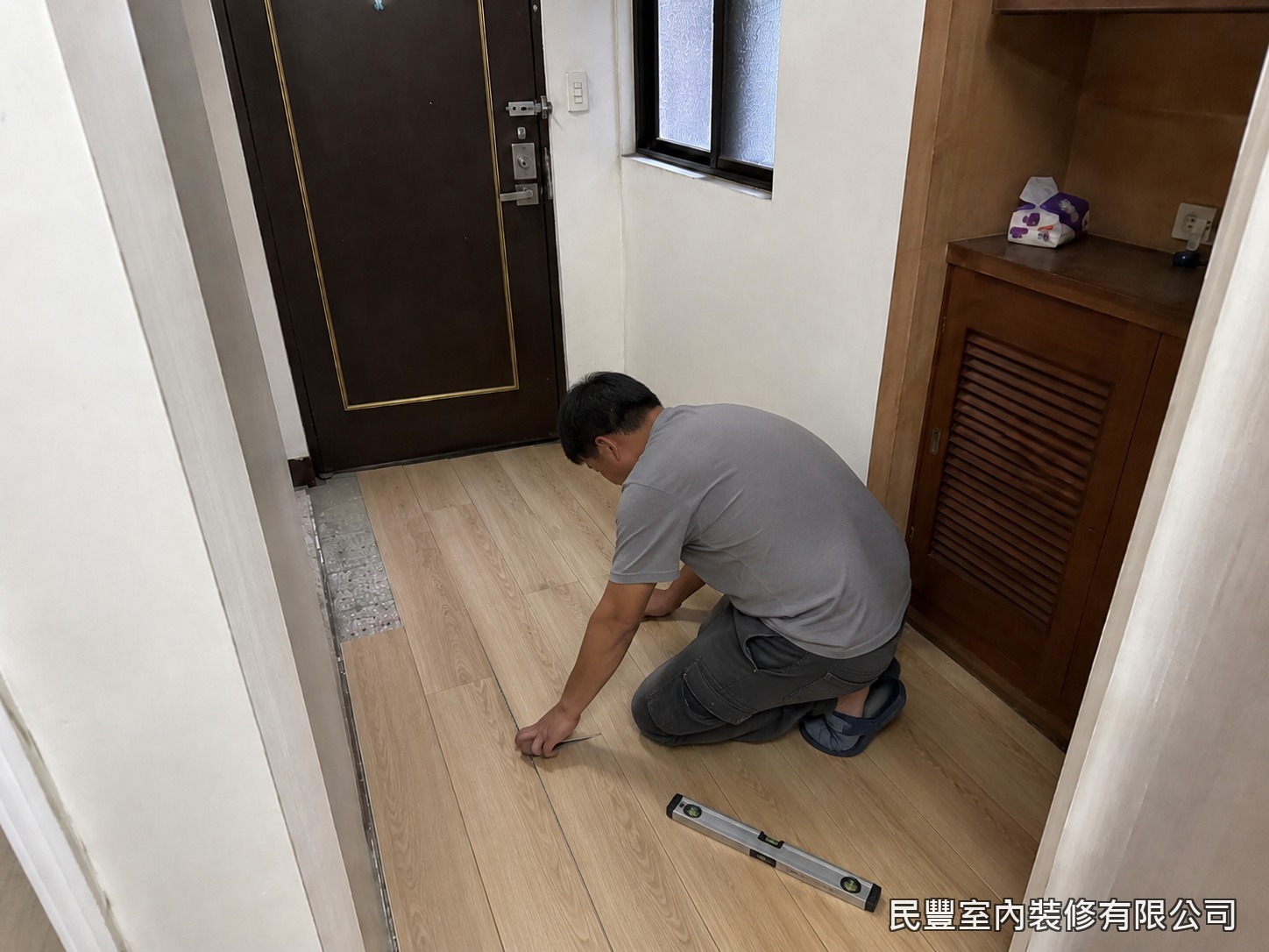 民豐室內裝修-SPC平鋪地板-師傅以卡扣平鋪工法逐片鋪設SPC石塑地板,水平尺隨時校驗,接縫緊密、面層平整