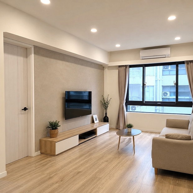 全室翻新整合施工-完工實景，客廳翻新完工，全新電視主牆以木皮板鋪貼，搭配木地板與新式冷氣，燈光明亮均勻，窗簾配置完善。整體風格現代簡約，業主擺入沙發後空間舒適宜人，整體翻新成果令人滿意